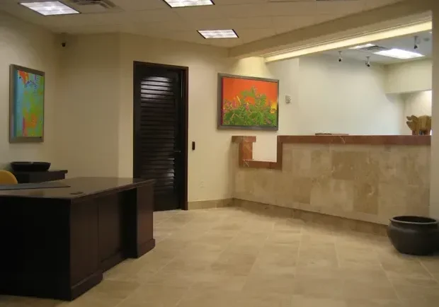 A reception area in a office with a painting on the wall.