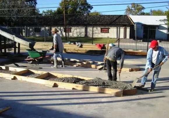 A group of people working on a concrete slab.